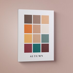 May include: A white canvas print with a color palette of 12 squares in shades of brown, orange, yellow, teal, and burgundy. The word "AUTUMN" is printed in black at the bottom of the print.