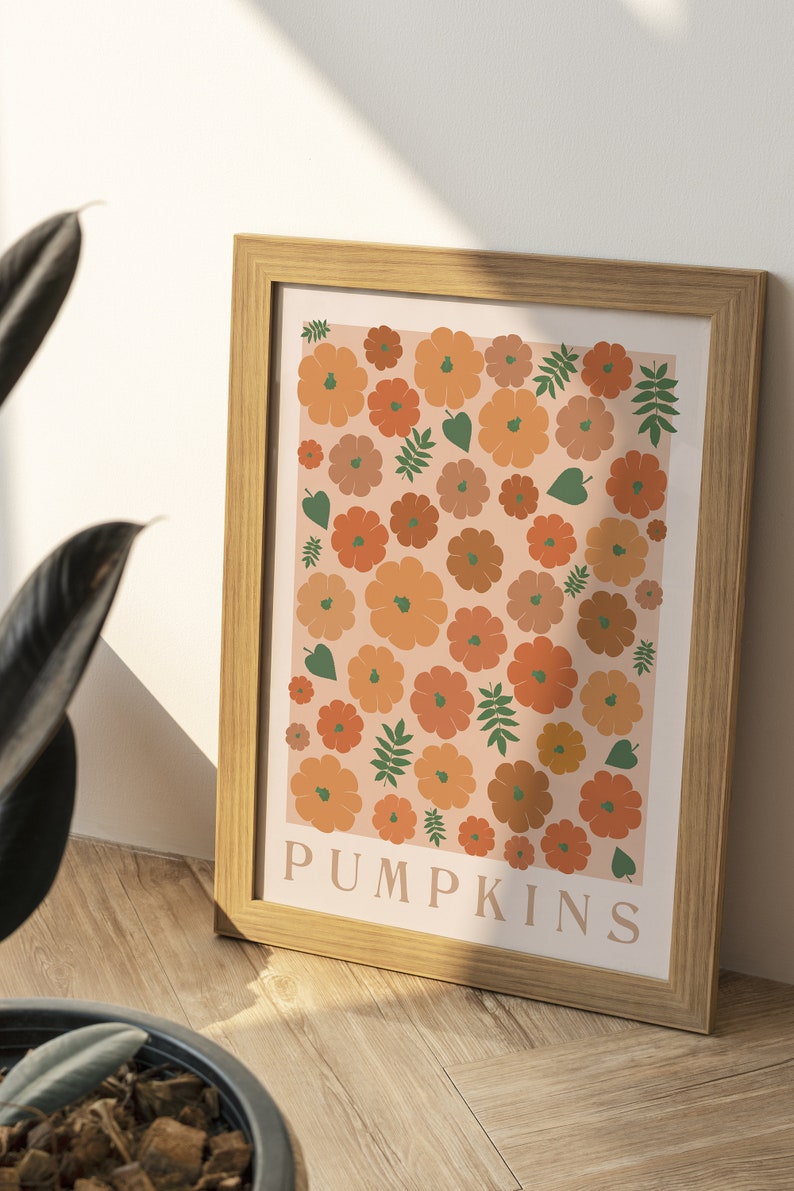 May include: A framed print featuring a pattern of orange and brown pumpkins on a pale pink background. The print has the word "PUMPKINS" at the bottom.