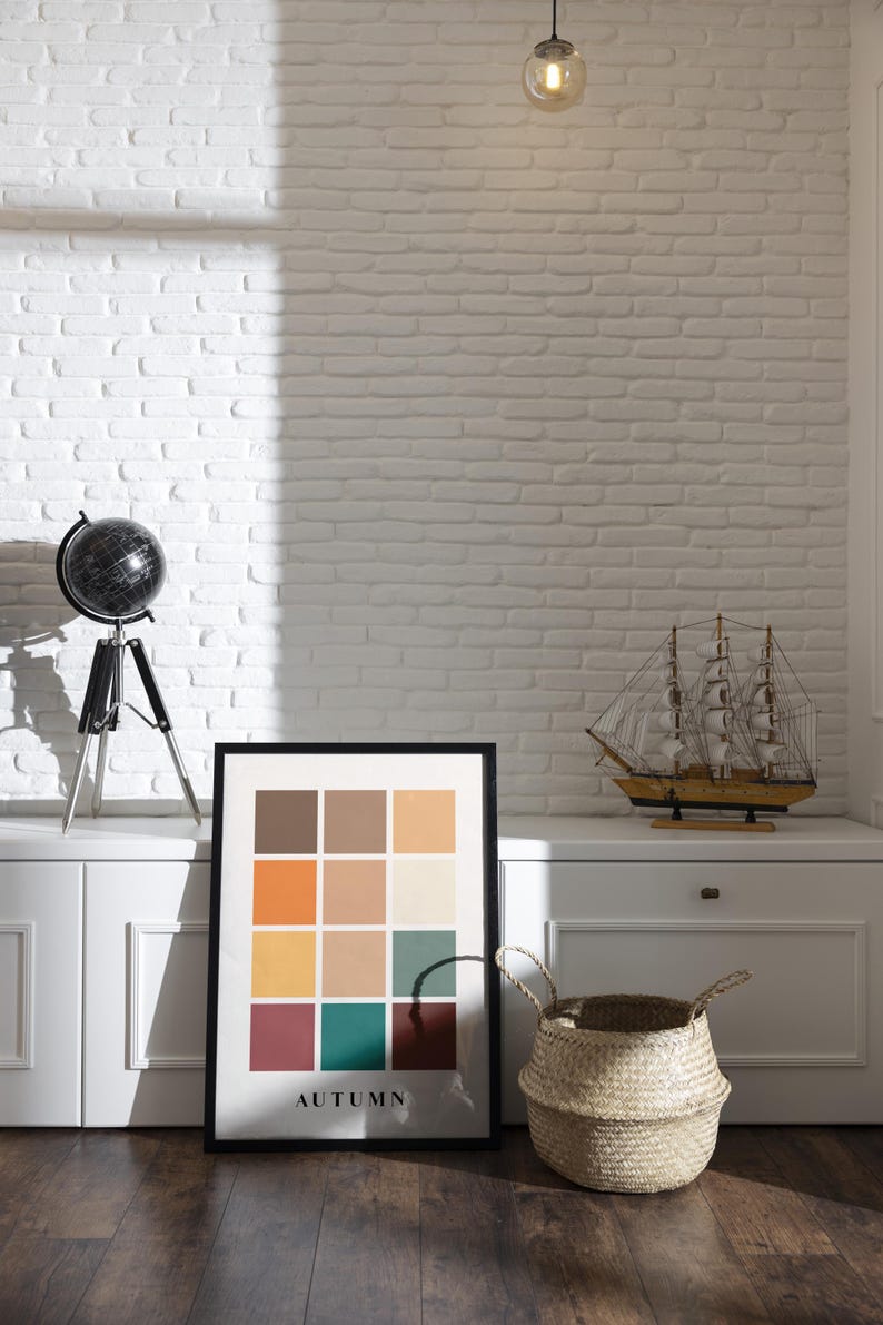 May include: A framed print with a color palette of autumnal colors, including orange, yellow, brown, red, and green. The print is titled "AUTUMN" and is displayed on a white shelf with a globe and a model sailboat.