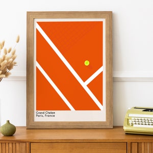 May include: A framed print of a tennis court with a yellow tennis ball in the center. The court is orange with white lines. The text "Grand Chelem Paris, France" is at the bottom of the print.
