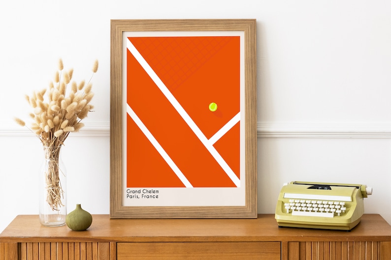 May include: A framed print of a tennis court with a yellow tennis ball in the center. The court is orange with white lines. The text "Grand Chelem Paris, France" is at the bottom of the print.