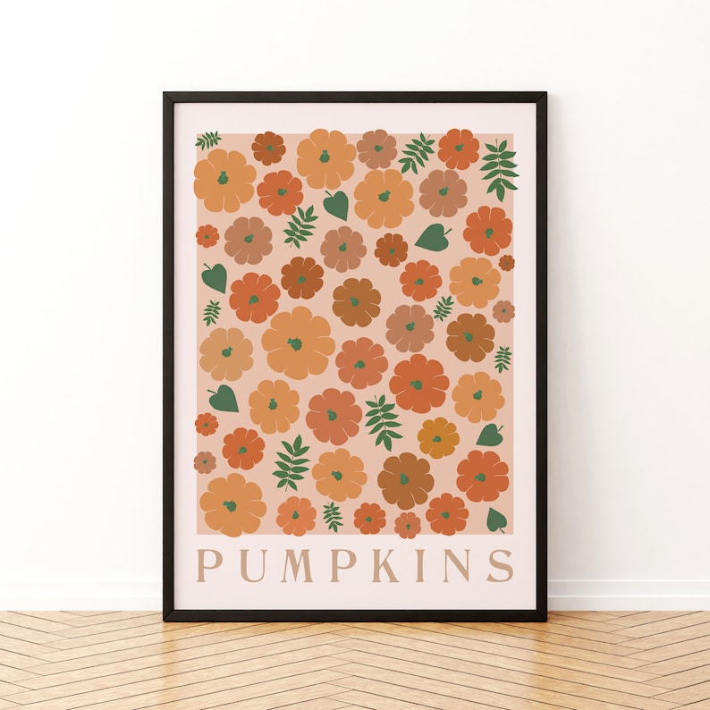 May include: A framed print with a peach background featuring a pattern of orange, brown, and green pumpkins and leaves. The text "PUMPKINS" is printed in black at the bottom of the print.