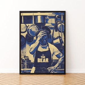 Könnte beinhalten: Ein blaues und gelbes Poster mit einem Mann, der eine schwarze Schürze mit dem Text "The Bear" trägt. Der Mann befindet sich in einer Küche mit Töpfen und Pfannen, die von der Decke hängen.