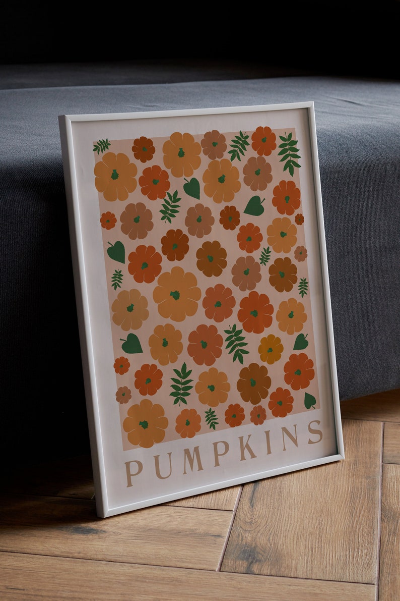 May include: A framed print featuring a pattern of orange, brown and green pumpkins and leaves on a pale pink background. The print has the word "PUMPKINS" in white text at the bottom.