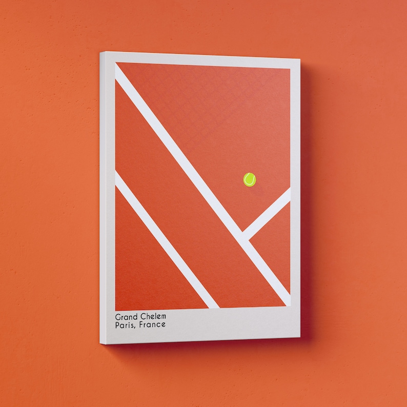 May include: A white framed print of a red clay tennis court with white lines and a yellow tennis ball. The print has the text "Grand Chelem Paris, France".