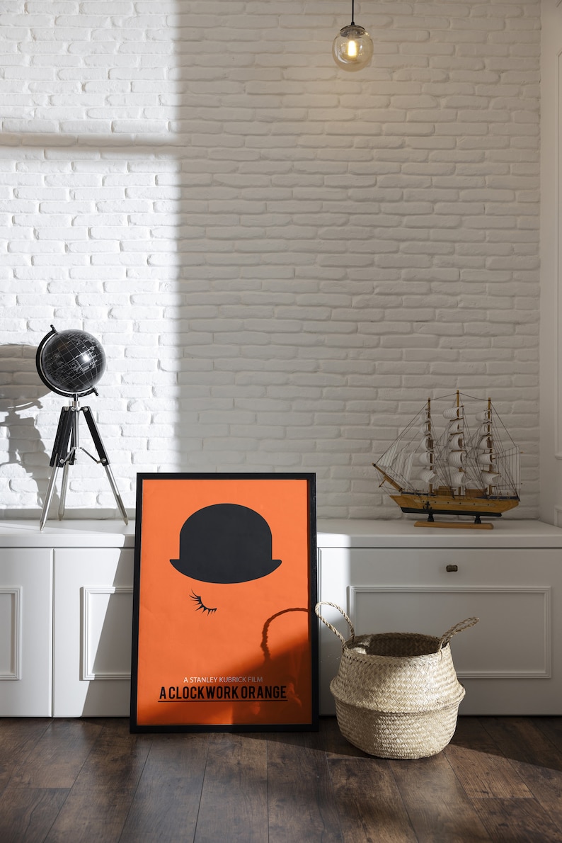 Puede incluir: Un p&oacute;ster en blanco y negro con fondo naranja que presenta la silueta de una persona con un sombrero de copa y el texto "A Stanley Kubrick Film: A Clockwork Orange".