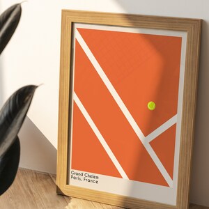 May include: A framed print of a tennis court with a yellow tennis ball in the center. The court is orange with white lines. The text "Grand Chelem Paris, France" is at the bottom of the print.