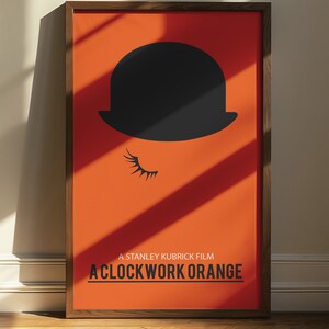 Puede incluir: Un p&oacute;ster enmarcado con fondo naranja y una silueta negra de un bomb&iacute;n con una pesta&ntilde;a. El texto "A Stanley Kubrick Film A Clockwork Orange" est&aacute; impreso en negro en la parte inferior del p&oacute;ster.