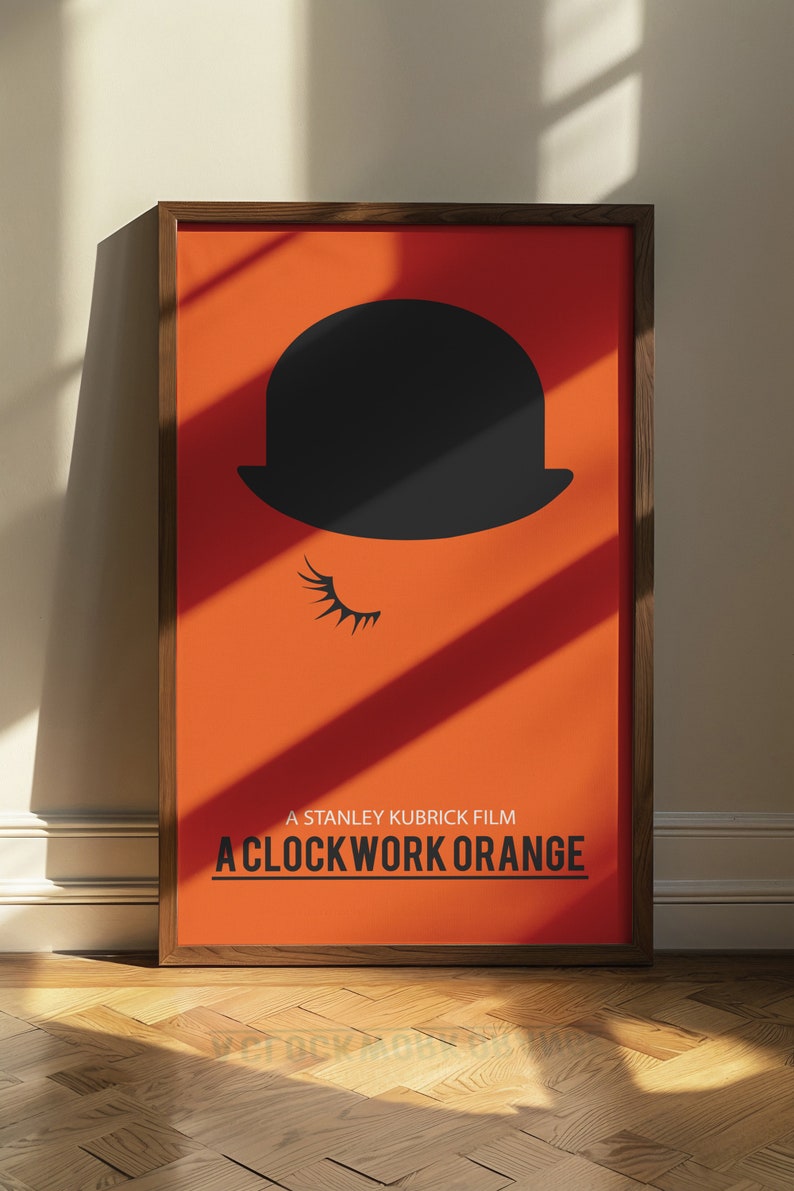 Puede incluir: Un p&oacute;ster enmarcado con fondo naranja y una silueta negra de un bomb&iacute;n con una pesta&ntilde;a. El texto "A Stanley Kubrick Film A Clockwork Orange" est&aacute; impreso en negro en la parte inferior del p&oacute;ster.