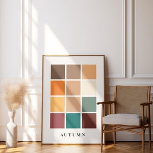 May include: A framed print with a grid of 12 colored squares in shades of brown, orange, yellow, green, and red. The word "AUTUMN" is printed below the grid.