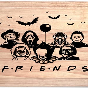 May include: Wooden chopping board with a handle, featuring black silhouettes of horror movie characters and bats. The word "FRIENDS" is written in black at the bottom. A decorative item for the kitchen.