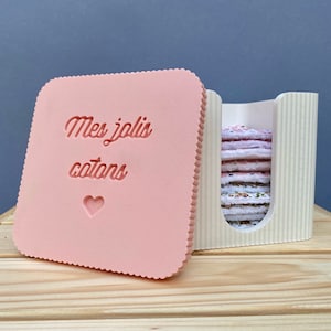 Peut inclure: Un contenant rose pour disques de coton avec un couvercle sur lequel est inscrit "Mes jolis cotons" et un petit cœur. Le contenant est doté d'un insert blanc avec une fente pour les disques de coton.