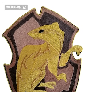 以下が含まれることがあります： ハリーポッターシリーズのハッフルパフ寮の紋章が刺繍されたパッチ。紋章は、茶色と黒の背景に黄色のアナグマが描かれた盾です。