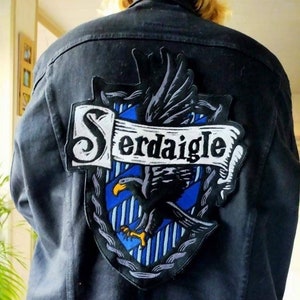 Può includere: Giacca di jeans nera con una toppa ricamata blu e grigia con un'aquila e il testo "Serdaigle".