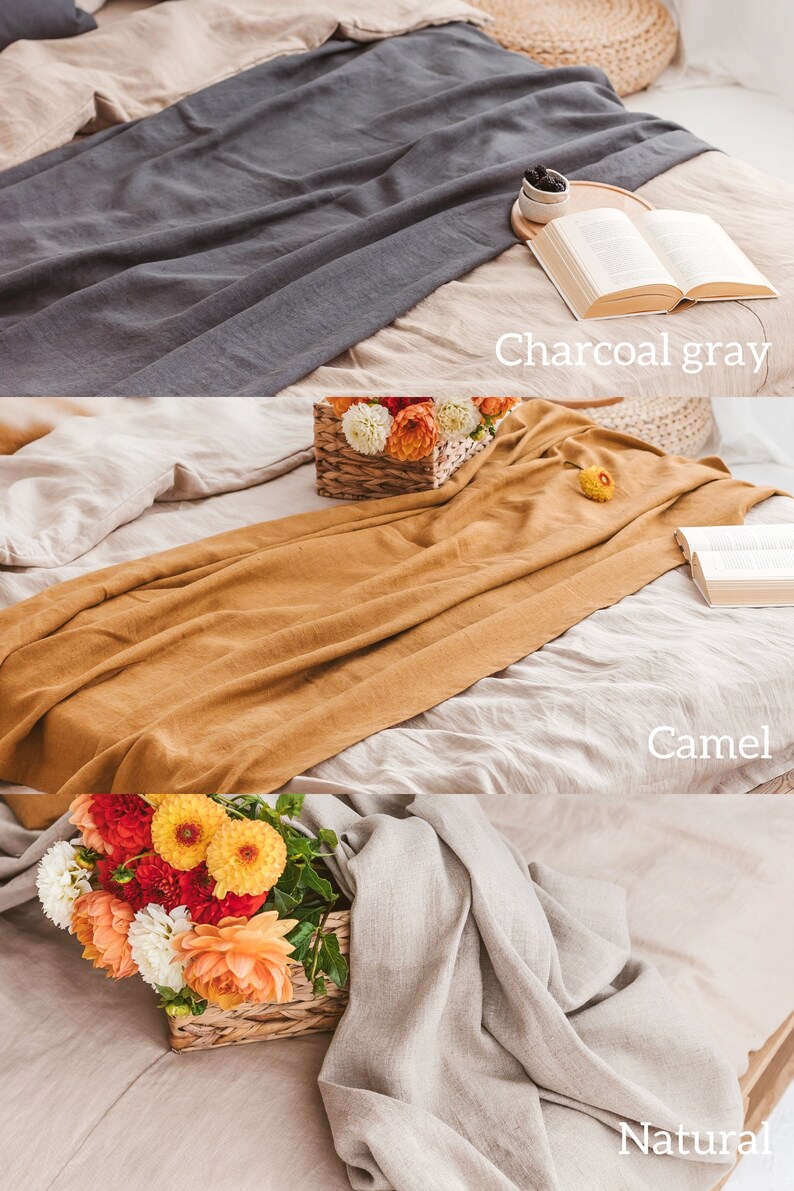 K&ouml;nnte beinhalten: Drei Bettw&auml;sche-Sets aus Leinen in verschiedenen Farben: Anthrazitgrau, Kamel und Natur. Die Sets sind auf einem Bett mit einem Blumenstrau&szlig; in einem Weidenkorb drapiert.