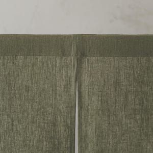 May include: A pair of green linen curtains with a subtle texture. The curtains are hung from a rod and are closed.