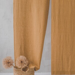 May include: A woven basket with a handle sits in front of a pair of mustard yellow linen curtains.