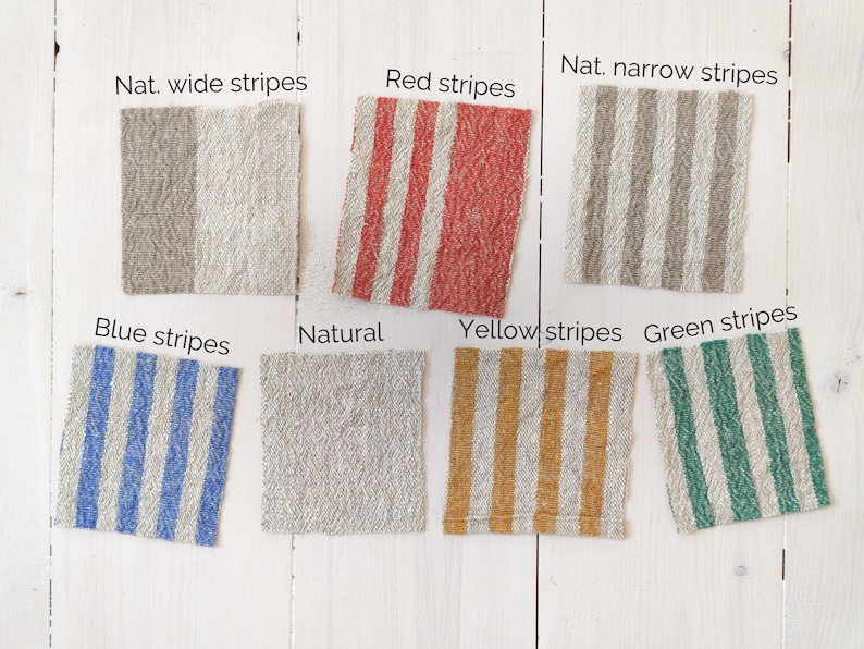 May include: A collection of fabric swatches in various colours and patterns, including natural, red, blue, yellow, and green stripes. The swatches are arranged in rows on a white wooden surface.