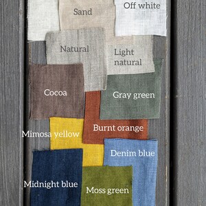 May include: A collection of fabric swatches in various colors, including cream, off white, sand, natural, light natural, cocoa, gray green, burnt orange, mimosa yellow, denim blue, midnight blue, and moss green.