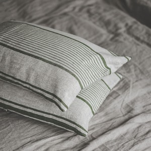 Può includere: Due federe a righe con strisce verdi su un lenzuolo da letto grigio.