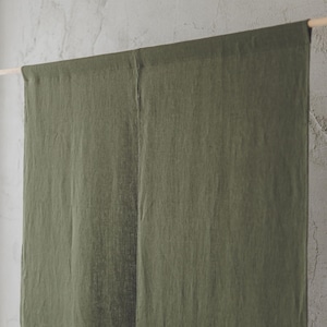 May include: A pair of olive green linen curtains hanging from a wooden rod. The curtains are made of a soft, textured fabric and have a simple, elegant design.