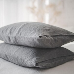 May include: Two gray linen pillowcases stacked on top of each other. The pillowcases are made of a soft, natural fabric and have a subtle texture.