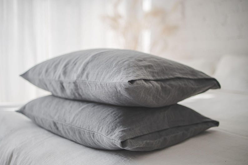 May include: Two gray linen pillowcases stacked on top of each other. The pillowcases are made of a soft, natural fabric and have a subtle texture.