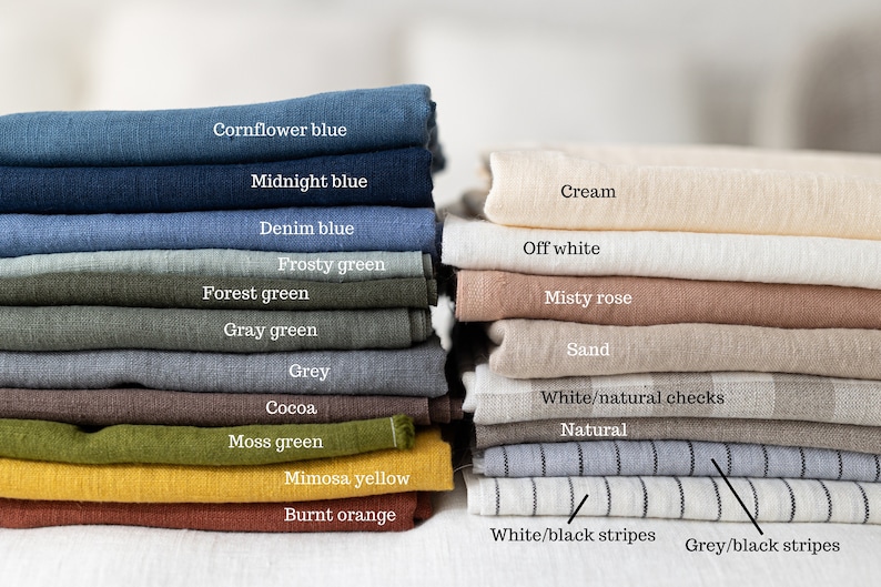 May include: A stack of linen fabric swatches in various colors, including cornflower blue, midnight blue, denim blue, frosty green, forest green, gray green, grey, cocoa, moss green, mimosa yellow, burnt orange, cream, off white, misty rose, sand, white/natural checks, natural, white/black stripes, and grey/black stripes.