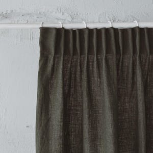 Op de afbeelding: Donkergroene linnen gordijnen die aan een witte gordijnroede hangen.