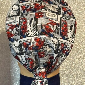 May include: A white fabric head wrap with a tie at the back. The fabric features a comic book pattern of Spiderman in various poses. The text on the fabric reads "This looks like a job for Spiderman!"