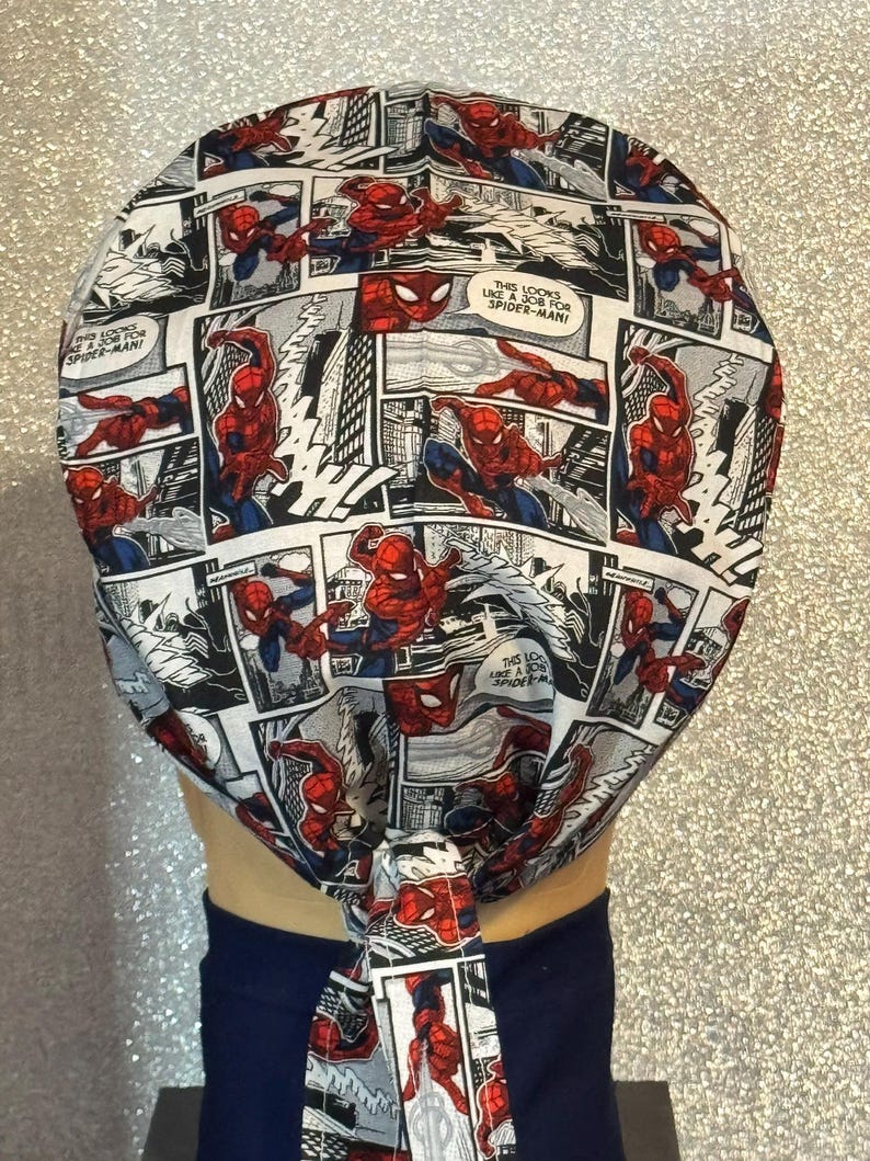 May include: A white fabric head wrap with a tie at the back. The fabric features a comic book pattern of Spiderman in various poses. The text on the fabric reads "This looks like a job for Spiderman!"