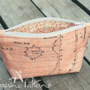 May include: A peach-coloured fabric pouch with a white zip, featuring a vintage sewing pattern design. The interior lining has a floral pattern. The text "Sleeve Puff" and "Passerine Patterns" are visible on the pouch.
