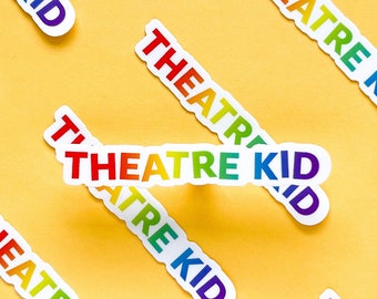 May include: A yellow background with rainbow colored stickers that say "Theatre Kid" scattered across the surface.