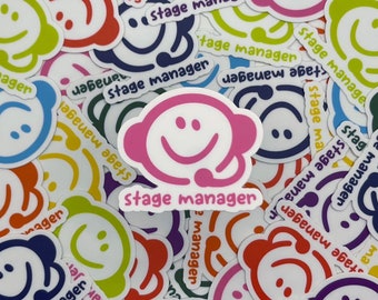 May include: A collection of colorful stickers featuring a smiling face with a headset and the words "stage manager." The stickers are in various colors, including pink, blue, green, yellow, orange, and purple, with white outlines.