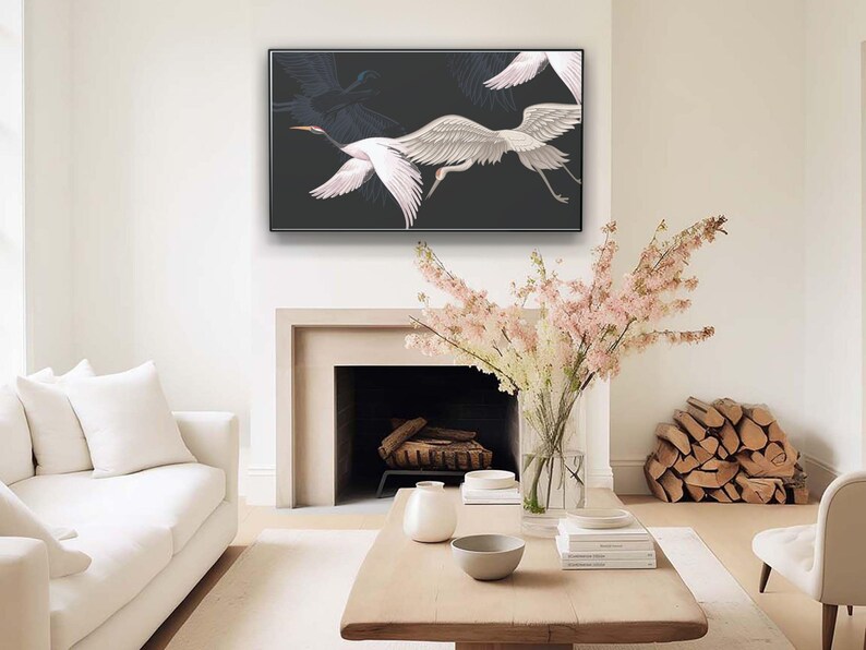 May include: A framed artwork featuring white cranes in flight against a dark background hangs above a fireplace. The artwork is the focal point of a living room with a white sofa, wooden coffee table, and decorative flowers.