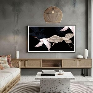 May include: A living room with a modern aesthetic. A large framed artwork on the wall features white and pink birds against a black background. The room includes a woven sofa, a coffee table, and a wooden cabinet.