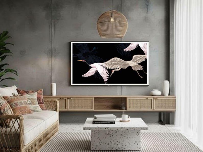 May include: A living room with a modern aesthetic. A large framed artwork on the wall features white and pink birds against a black background. The room includes a woven sofa, a coffee table, and a wooden cabinet.