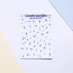 May include: A sticker sheet with blue star stickers in various shades of blue. The sheet is white and has the text "Lavender Love Store" and "Blue Stars Sticker Sheet" printed on it.