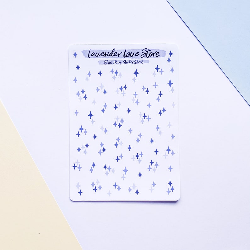 May include: A sticker sheet with blue star stickers in various shades of blue. The sheet is white and has the text "Lavender Love Store" and "Blue Stars Sticker Sheet" printed on it.