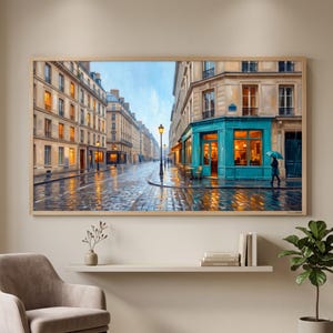 May include: A framed wall art print depicting a rainy Parisian street scene with wet cobblestone pavement, tall beige buildings, and a vibrant turquoise storefront. A person with a teal umbrella walks near the corner under a street lamp.