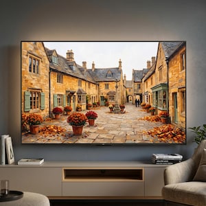 May include: A large flat-screen television mounted on a wall displays a painting of a European village square with golden stone buildings, light green shutters, and terracotta pots filled with vibrant orange and red flowers on a stone path.