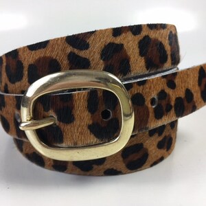 May include: A brown and black leopard print belt with a gold oval buckle.