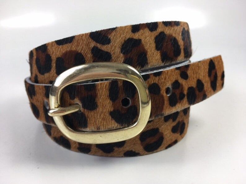 May include: A brown and black leopard print belt with a gold oval buckle.