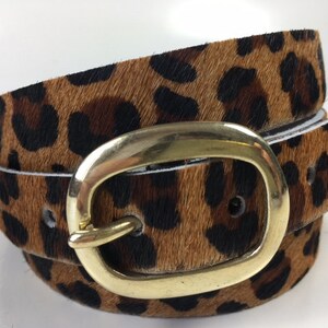 May include: A brown and black leopard print belt with a gold oval buckle.