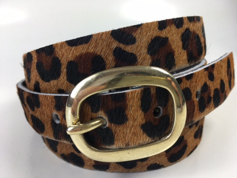 May include: A brown and black leopard print belt with a gold oval buckle.