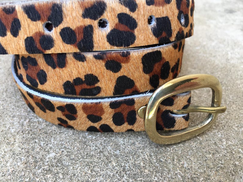 May include: A brown and black leopard print belt with a gold metal buckle.