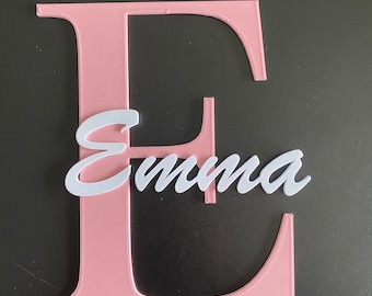 May include: A pink letter E with the name Emma written in white cursive letters on top of it.