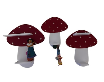 May include: Three white mushroom-shaped shelves with red tops and white polka dots. The shelves are mounted on a white wall.