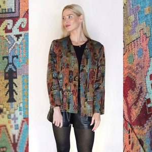 Könnte beinhalten: Eine bunte, gemusterte Jacke mit geometrischem Design. Die Jacke ist offen und hat lange Ärmel. Der Stoff ist eine tapisserieartige Webart.