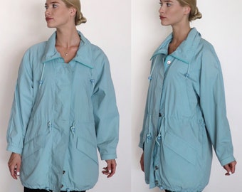 May include: A light blue jacket with a drawstring waist and a zipper closure. The jacket has a high collar and long sleeves.